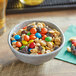A bowl of Trail Mix with peanuts, raisins, and M&M's on a table.