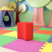 A red cube on a colorful surface in a playroom.