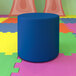 A blue cylindrical Flash Furniture Nicholas ottoman on a colorful mat.