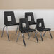 A group of four black Flash Furniture Mickey Advantage stackable chairs with metal legs and square cutouts in a room.