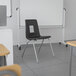 A black Flash Furniture Mickey Advantage stackable chair in a classroom.