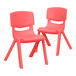A pair of red plastic chairs with pink legs.