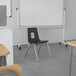 A black Flash Furniture Mickey Advantage classroom chair with silver legs in a classroom.