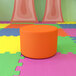A Flash Furniture Nicholas orange round modular ottoman on a colorful surface.