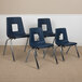 A group of four Flash Furniture navy blue plastic stackable classroom chairs with metal legs.