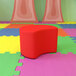 A red Flash Furniture Nicholas moon ottoman on a colorful floor.