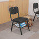 A black Flash Furniture plastic chair with a wire basket on the bottom with a stack of chairs.