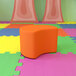 A Flash Furniture Nicholas orange soft seating moon ottoman on a colorful surface.