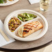 A World Centric compostable fiber plate with salmon, vegetables, and a lemon slice on it on a table.
