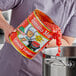 A person pouring Stanislaus Tomato Magic ground peeled tomatoes into a pot.