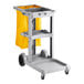 A Lavex gray janitor cart with a yellow bag on a shelf.