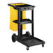 A black Lavex janitor cart with yellow accents and a yellow bag.