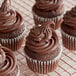 A group of chocolate cupcakes with chocolate frosting on a cooling rack.