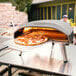 A pizza being cooked in a Ooni Koda 16 portable pizza oven.