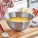 A person mixing eggs in a large Matfer Bourgeat stainless steel bowl.