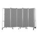 A National Public Seating grey room divider with 5 grey fabric panels and wheels.