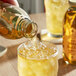 A hand pouring Harney & Sons Organic Soba Green Iced Tea into a glass with ice.