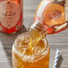 A bottle of Harney & Sons Organic Peach Iced Tea being poured into a glass.