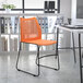 An orange Flash Furniture Hercules stacking chair with black sled base at a white table.