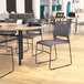 A Flash Furniture Hercules gray diamond ventilated stacking chair with a black sled base on a table in a room.