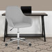 A Flash Furniture Cortana light gray office chair with wheels next to a desk.