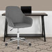 A Flash Furniture Cortana gray leather office chair with wheels next to a desk.