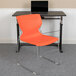 A Flash Furniture Hercules orange stacking chair with a gray sled base sits next to a table.