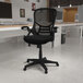 A Flash Furniture black mesh high-back office chair in a room with a grey wall.