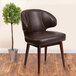 A Flash Furniture brown leather chair with walnut legs next to a potted plant.