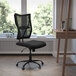 A Flash Furniture Hercules black mesh big and tall office chair in front of a wooden desk with a laptop and a book on it.