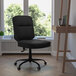 A Flash Furniture black leather office chair at a wooden desk.