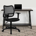A Flash Furniture black mesh office chair with adjustable arms at a desk with a laptop.