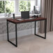 A Flash Furniture Tiverton mahogany and black office desk with a laptop on it.