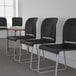 A row of three Flash Furniture black full-back stacking chairs with gray sled bases.