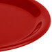 A close-up of a red Carlisle Sierrus melamine pie plate with a shiny rim and curved edge.