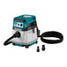 A Makita vacuum cleaner with a hose on a table.