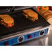 A Globe Panini Sandwich Grill with two sandwiches cooking.