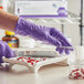 A person in Kimtech purple gloves cutting pills on a tray.