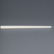 An ivory Will & Baumer taper candle in a white tube on a gray surface.