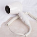 A white Conair wall mount hair dryer sitting on a white towel.