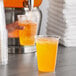 A hand pouring orange Gatorade powder into a plastic cup.