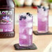 A glass of purple Lotus 5:1 Energy Concentrate with ice and blueberries.