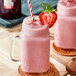 A pink smoothie made with SHOTT Strawberry Real Fruit Flavoring Syrup in a glass jar with a straw.