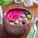 A bowl of pink smoothie with fruit and seeds.