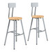 Two National Public Seating lab stools with oak seats and steel legs.