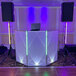 A white dj booth with Ape Labs Stick XL 2.0 LED lights on stands.