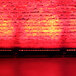 A red Prost Lighting WonderBar LED wash light on a brick wall.