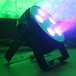 A Prost Lighting StillPar 5 LED wash light with green, blue, and purple lights on a stand.