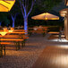 Ape Labs Stick 2.0 wireless LED lights on tables with umbrellas on a wooden deck.