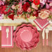 A table setting with Sophistiplate Berry Scalloped Edge paper guest towels, pink plates, and flowers.